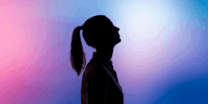 Silhouette einer Frau im Profil vor einem farbigen Hintergrund in Blau- und Rosatönen